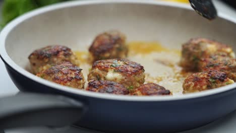 unrecognizable person cooking meatballs on frying pan with oil