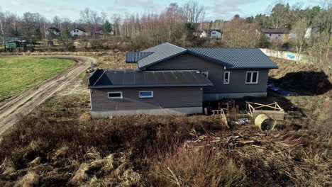 newly constructed modern house with dirt driveway in muddy field