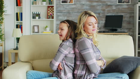 little girl with bad behavior sitting back to back with her mother