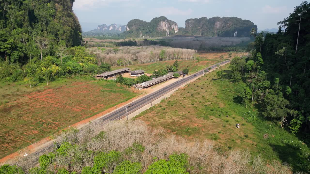 Rural road cutting through lush greenery and limestone hills in Krabi, Thailand
