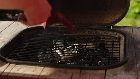 unrecognizable man putting beef meat on the bbq or barbecue grill in sweden on a warm summer day