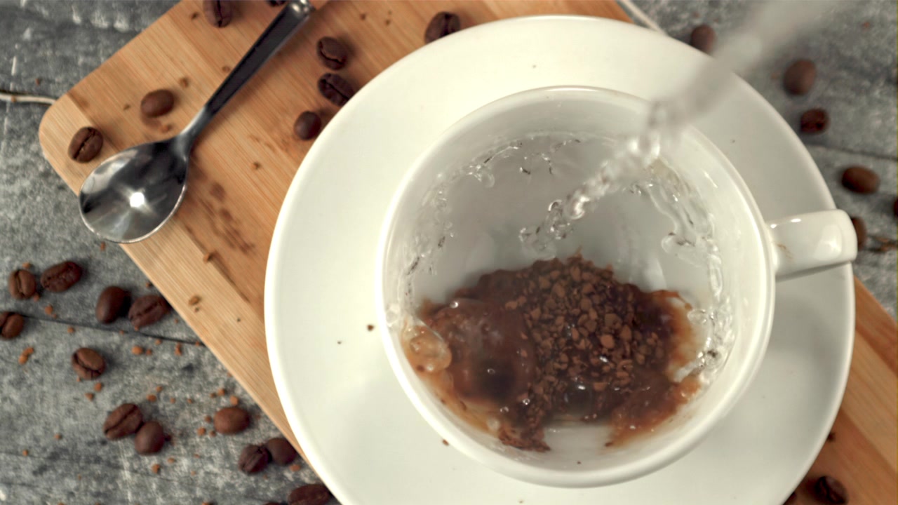 Vertiendo agua caliente en una taza de café instantáneo