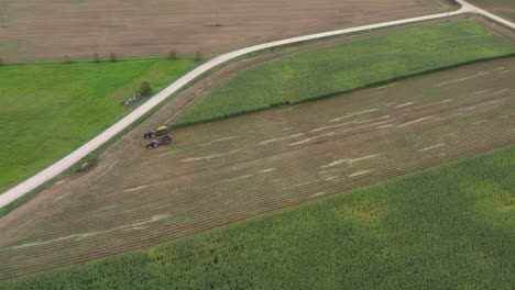 Vista-De-Pájaro-De-Los-Tractores-Agrícolas-En-El-Campo-Triturando-Tallos-De-Maíz-Para-Alimentar-Al-Ganado