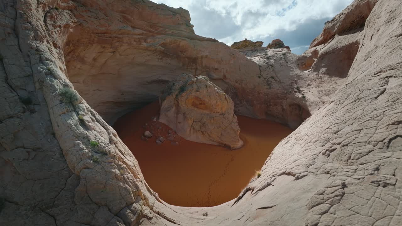 Detailní záběr dronem na pískovcovou mísu Cosmic Ashtray obsahující oranžový písek v poušti Utah.