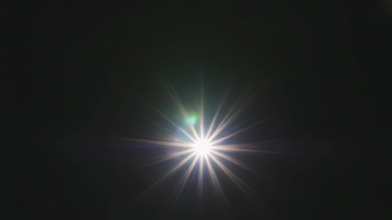 Luce a raggiera pulsante che emerge dal nero, inviando una scia verticale di bagliori, illuminando un bordo bianco strappato