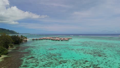 Cinematic-drone-flight-across-lagoon-in-Tahiti-with-overwater-bungalows-at-hotel-resort