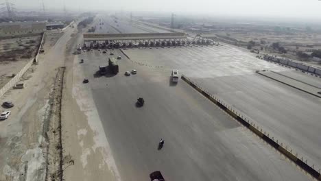 Vista-Aérea-De-Una-Plaza-De-Peaje-De-La-Autopista-De-La-Ciudad,-Vehículos-Pesados-Y-Otros-Que-Ingresan-Y-Cruzan