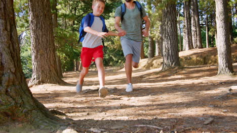 father and son on hiking adventure running through forest