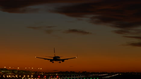 Tracking-shot-of-airplane-landing-at-airport-during-cinematic-twilight