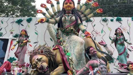 round faced durga idol with snake in her hand attacking asur. durga puja carnival procession.