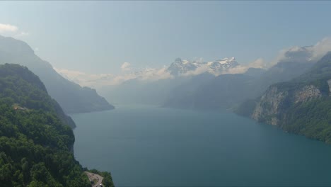 Paso-Elevado-De-Morschach:-Moviéndose-Sobre-El-Pintoresco-Valle-De-Agua-Hacia-Las-Montañas-De-Los-Alpes,-Suiza,-Europa,-Drone-|-Movimiento-Lento-Cerca-Del-Acantilado-De-La-Carretera-Escénica-Hacia-La-Montaña