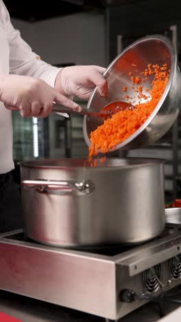 chef adding chopped carrots to a pot