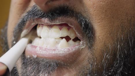 a close-up, slow-motion footage of a young man brushing his teeth, with a blurred background. dental care and hygiene concept
