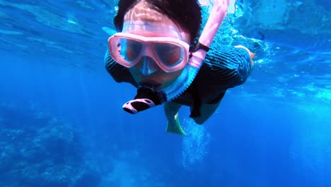 close up of young adventurous woman snorkelling over tropical coral reef