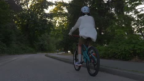 young adult biking on the street at sunset