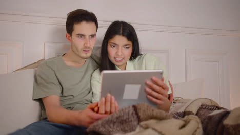 Couple-Watching-Unpleasant-Movie-Scene-On-Laptop-Sitting-On-Bed-At-Home