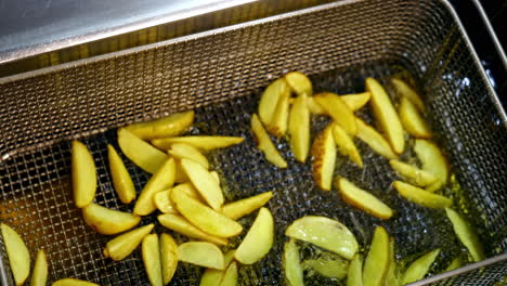 pieces of potato in deep fryer before cooking. many bubbles appears in hot oil. process of frying potato in boiled oil.