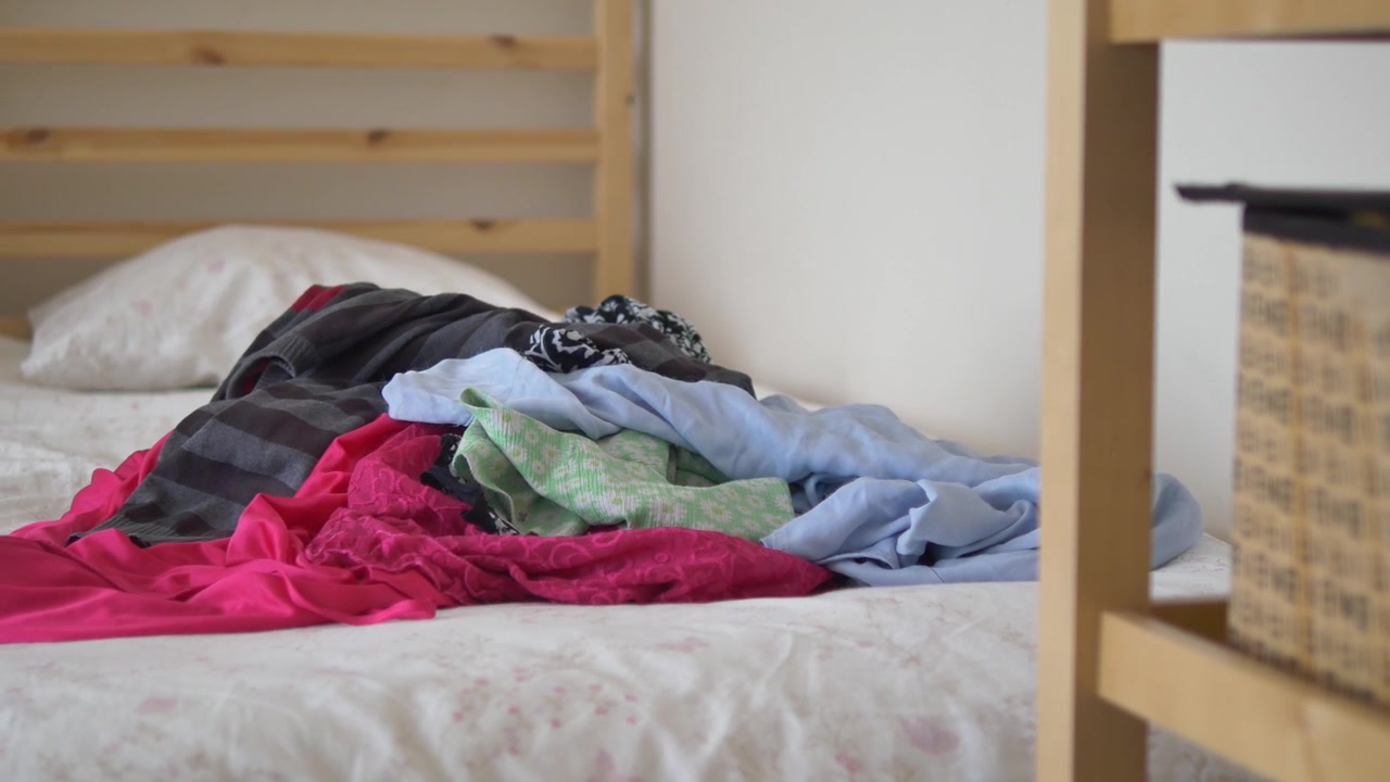 Pile of Unfolded Laundry on a Bed in a Bedroom
