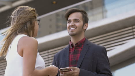 Business-people-holding-cell-phones-and-talking-on-street