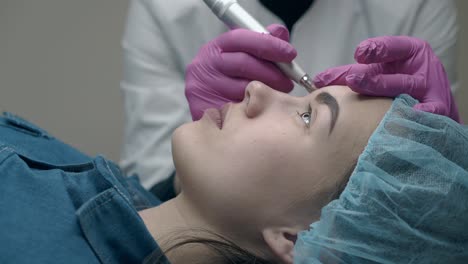 la morena se acuesta con los ojos abiertos y la cosmetóloga aplica maquillaje