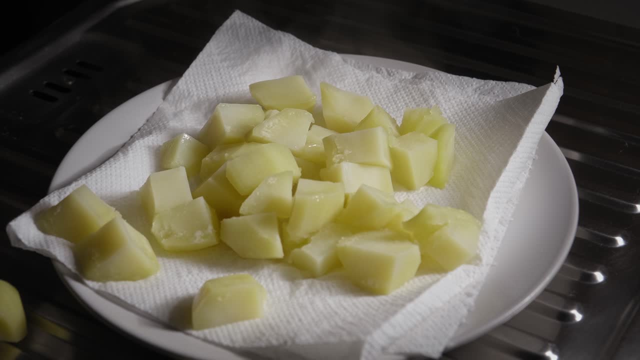 papas hervidas secándose en papel antes de freírse en una sartén, cocinando vegetariano