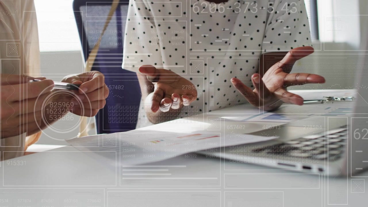 Right woman pointing and left woman reviewing docs with pen, UI overlay highlighting business data