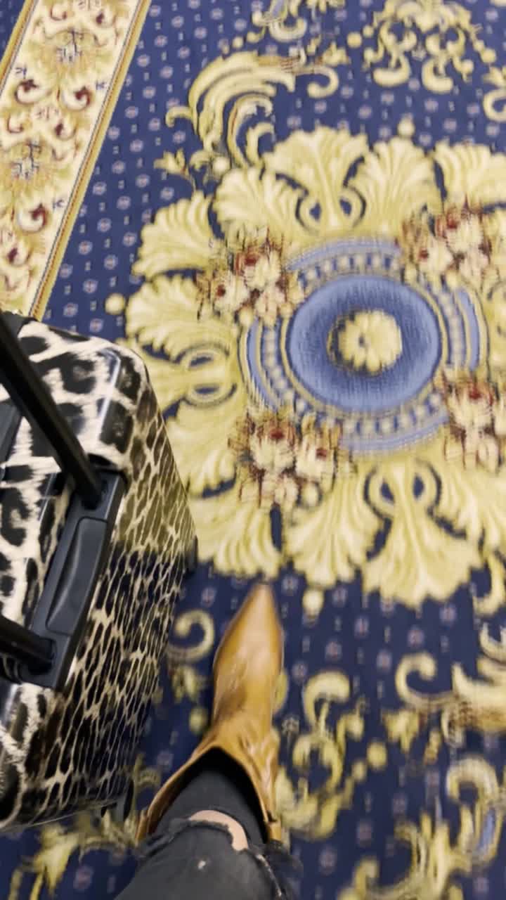 Persona che cammina e trascina una valigia leopardata su un tappeto a motivi