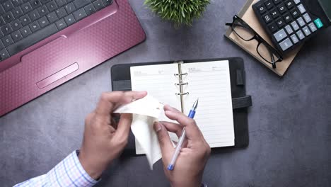 person writing in a notebook at a desk