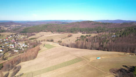 Aerial-forward-view-of-village-with-fields-and-forest