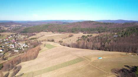 Vista-Aérea-Hacia-Adelante-Del-Pueblo-Con-Campos-Y-Bosques