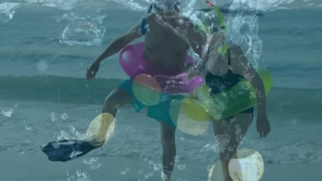 senior couple enjoying at the beach against multiple coins falling in the water