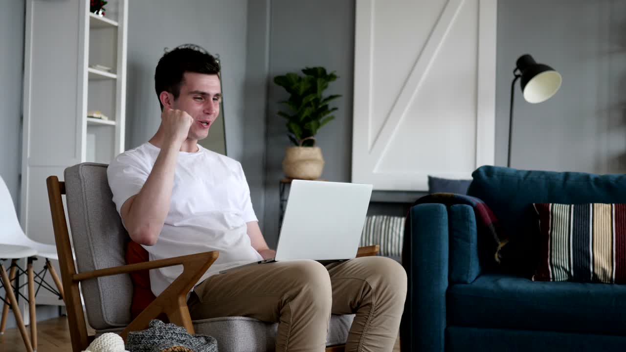 un hombre emocionado celebrando el éxito en su computadora portátil.
