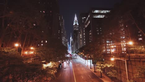 nyc: tudor city bridge view at night, with the chrysler building and midtown skyscrapers in the distance and traffic passing below  - new york city, usa