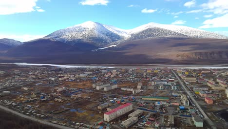 una pequeña ciudad contra el telón de fondo de las montañas cubiertas de nieve de un drone 4k