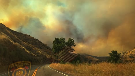 pov driving shot inside a firefighter car, in middle of wildfire smoke and hills in california, usa - fireman batch and a us flag reflecting from the window