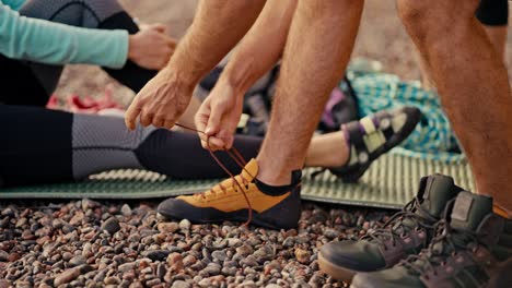 close-up shot of a man putting on special climbing shoes as he prepares to climb on a rocky seashore. man rock puts on special shoes and sneakers to start pounding the rock