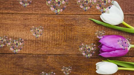 Animation-of-flower-hearts-floating-over-wooden-surface-with-tulips