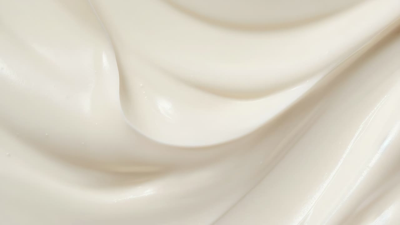 Primo piano, vista dall'alto di una texture bianca, liscia e cremosa, che ricorda una lozione o uno yogurt