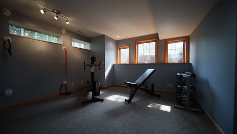 workout room with a bike, bench, and dumbbells with sunlight peaking through the windows