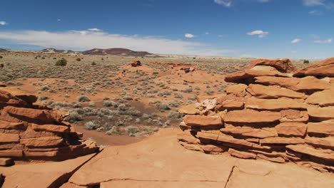 Una-Vista-Del-Desierto-Más-Allá-De-Las-Ruinas-Del-Pueblo-De-Wukoki-Desde-Lo-Alto-De-Una-Plataforma-De-Piedra-Natural-Con-Un-Límite-De-Muro-De-Piedra-En-El-Monumento-Nacional-De-Wupatki-En-Arizona