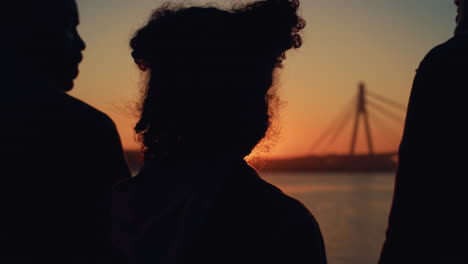 curly girl silhouette standing with parents at golden sunset rear view closeup.