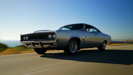 a vintage muscle car driving on a scenic coastal road