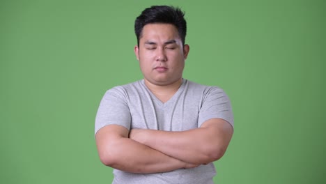 young handsome overweight asian man against green background