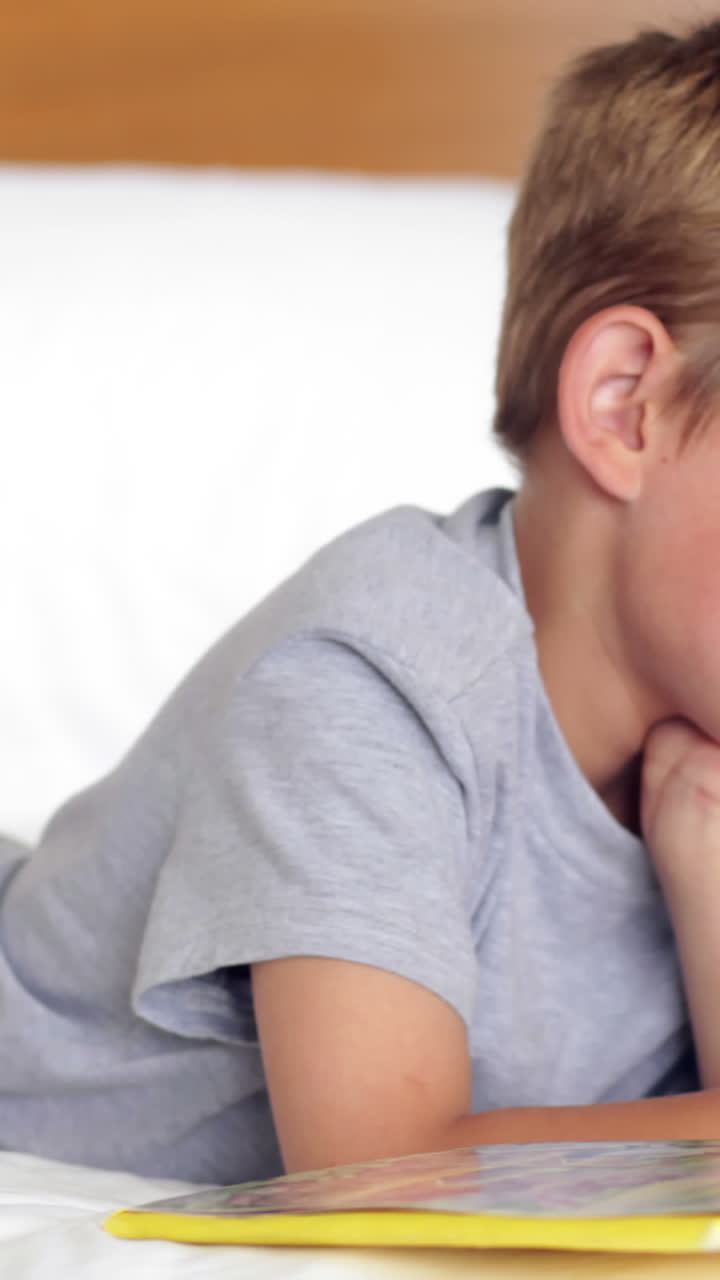 Bambino sdraiato a letto che legge un libro
