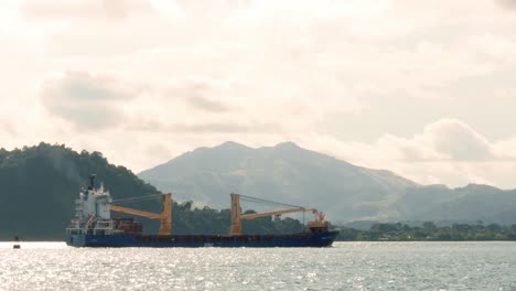 bbc fuji cargo ship navegating through the panama canal embankment in early morning with cloudy blue skies and tropical forests on the background while the vessel transports freight aroung the world