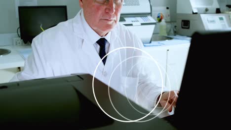 Animation-of-circles-spinning-over-male-scientist-using-computer