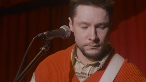 male musician playing guitar and singing during live music perfomance