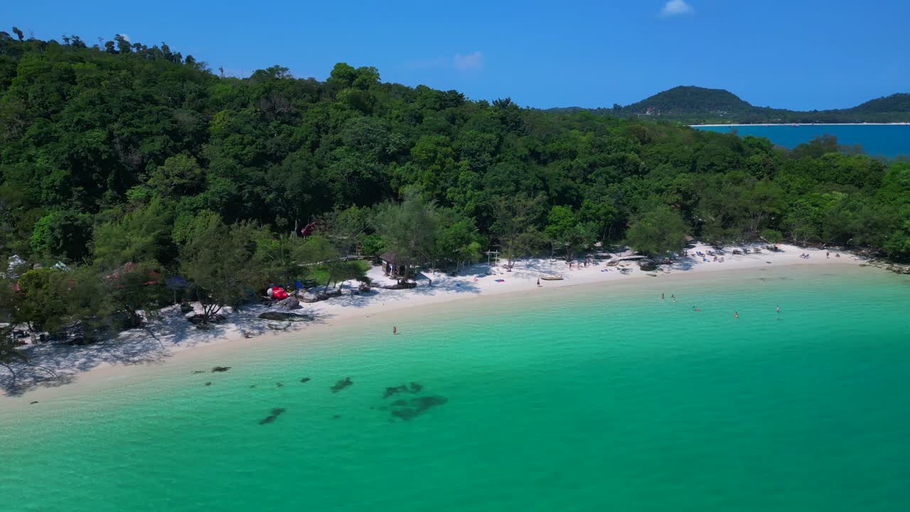 Tourists enjoying the white sand Kaoh Touch Beach and turquoise waters of Koh Rong, a tropical island paradise in Cambodia. Wonderful aerial view flight panorama orbit drone