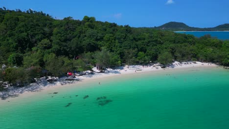 tourists enjoying the white sand kaoh touch beach and turquoise waters of koh rong, a tropical island paradise in cambodia. wonderful aerial view flight panorama orbit drone