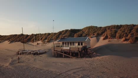 sail boat house on the beach while the sun is setting